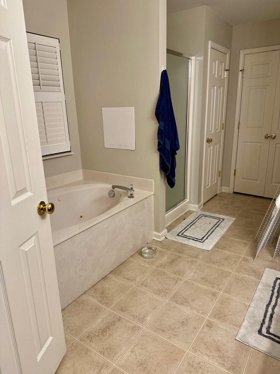 Bathroom before renovation, with a built-in tub, enclosed shower and beige floor tile